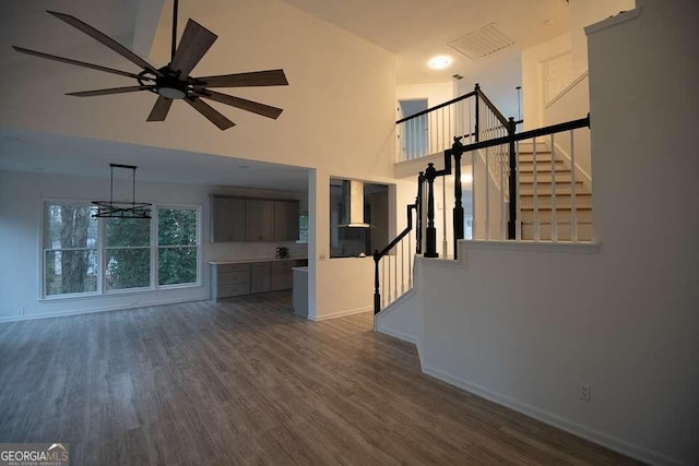 unfurnished living room with ceiling fan, dark hardwood / wood-style flooring, and a towering ceiling