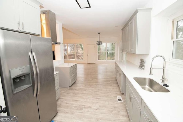 kitchen with gray cabinetry, sink, stainless steel fridge with ice dispenser, light hardwood / wood-style flooring, and decorative light fixtures