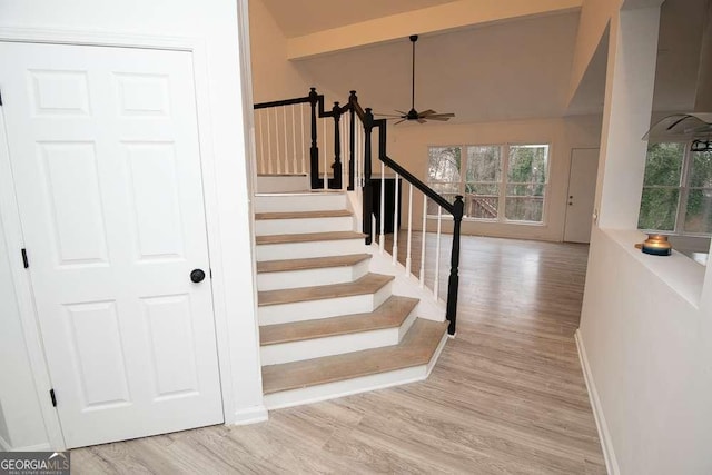 stairway featuring ceiling fan, wood-type flooring, and high vaulted ceiling