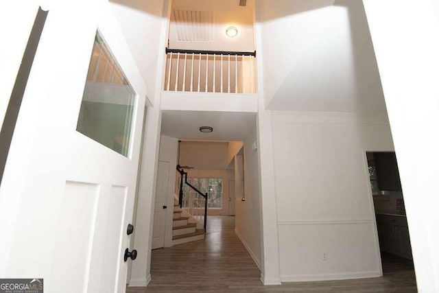 corridor featuring a high ceiling and dark hardwood / wood-style flooring