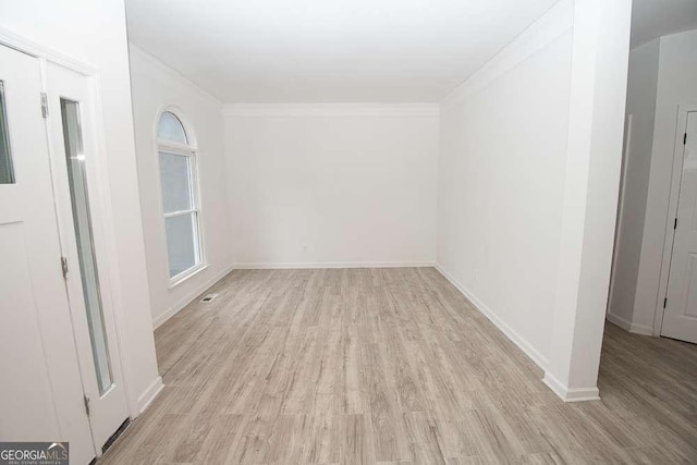 unfurnished room with light wood-type flooring and crown molding