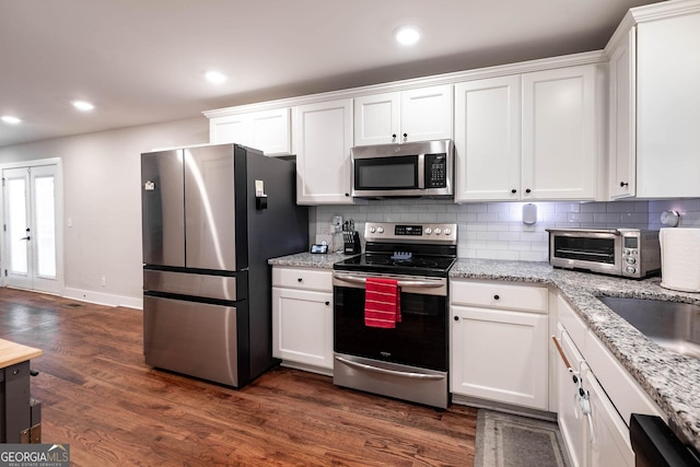 kitchen featuring white cabinetry, dark hardwood / wood-style floors, tasteful backsplash, light stone countertops, and appliances with stainless steel finishes