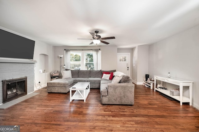 living room with a fireplace, ceiling fan, and dark hardwood / wood-style floors