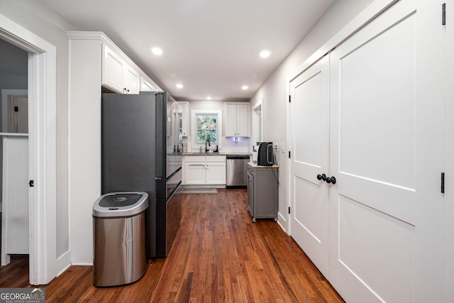 kitchen featuring sink, white cabinetry, backsplash, dark hardwood / wood-style floors, and appliances with stainless steel finishes