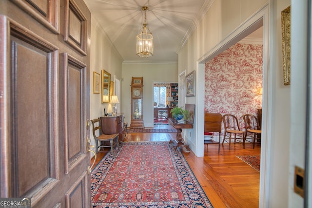 foyer with an inviting chandelier, hardwood / wood-style floors, and crown molding