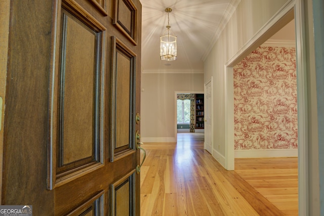 interior space with baseboards, ornamental molding, light wood-style floors, and an inviting chandelier