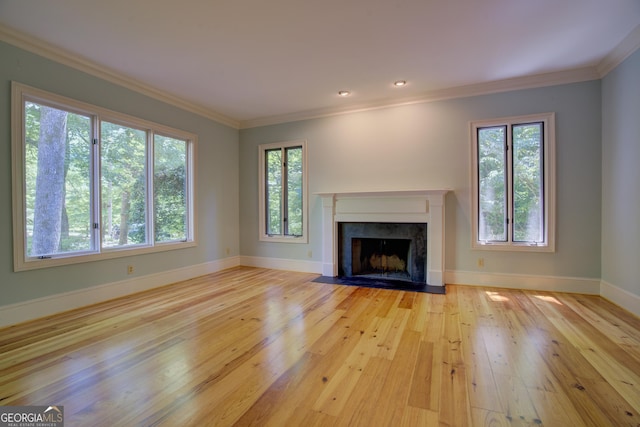 unfurnished living room featuring light wood finished floors, a premium fireplace, baseboards, and crown molding