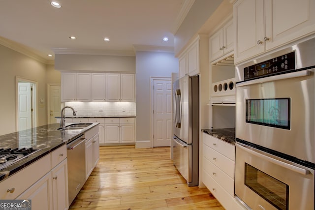 kitchen with stainless steel appliances, white cabinets, crown molding, and a sink