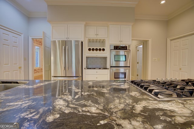 kitchen featuring recessed lighting, white cabinetry, appliances with stainless steel finishes, dark stone counters, and crown molding