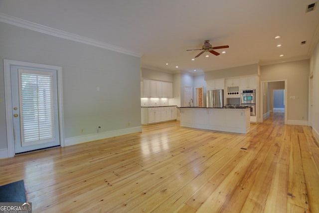 unfurnished living room with a sink, visible vents, baseboards, light wood-type flooring, and crown molding