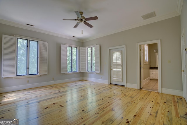 unfurnished room featuring ornamental molding, light wood-type flooring, visible vents, and baseboards