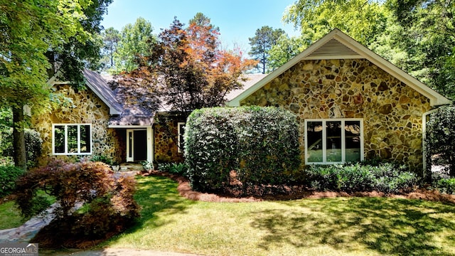 obstructed view of property with a front yard and stone siding