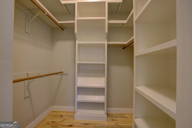 walk in closet with light wood finished floors