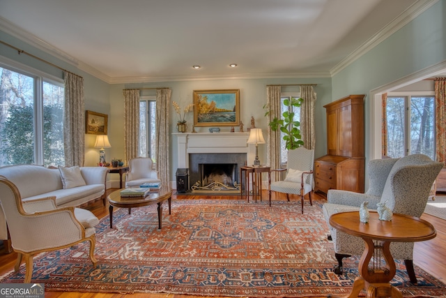 living area with a fireplace with flush hearth, wood finished floors, and crown molding