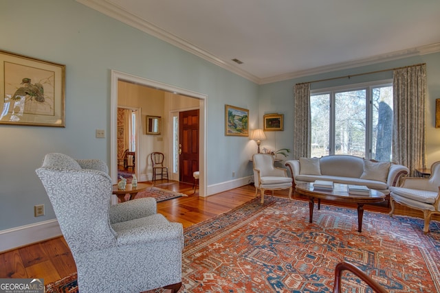 living room with baseboards, wood finished floors, visible vents, and crown molding