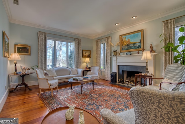 living room with a fireplace with flush hearth, a healthy amount of sunlight, crown molding, and wood finished floors