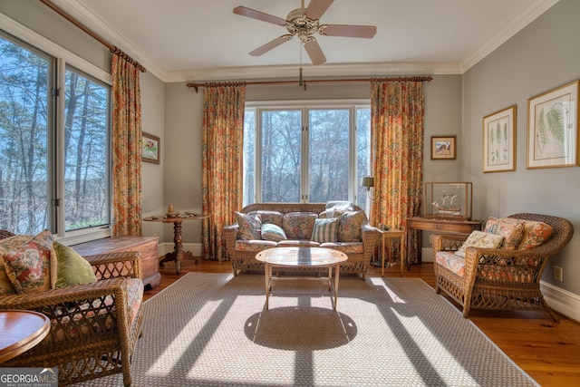 living area with ceiling fan, crown molding, baseboards, and wood finished floors