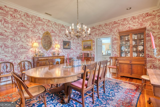 dining space with wallpapered walls, visible vents, wood finished floors, crown molding, and a chandelier