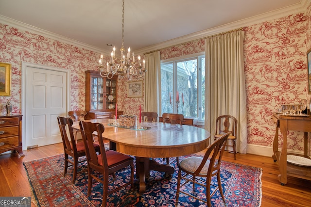 dining room with wallpapered walls, baseboards, hardwood / wood-style flooring, ornamental molding, and a chandelier