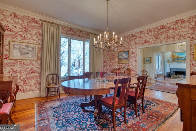 dining area with hardwood / wood-style flooring, a fireplace, baseboards, ornamental molding, and wallpapered walls