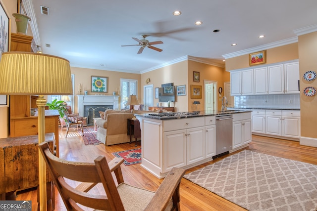 kitchen with a center island with sink, visible vents, white cabinets, stainless steel dishwasher, and a sink