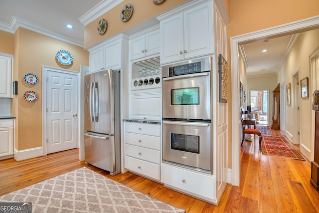 kitchen featuring appliances with stainless steel finishes, white cabinetry, crown molding, and light wood finished floors