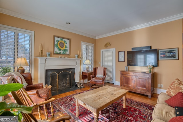 living area with a fireplace with flush hearth, ornamental molding, baseboards, and wood finished floors