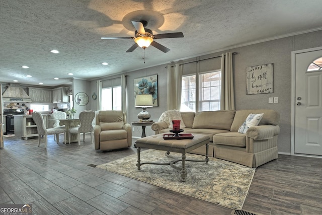 living room with a wealth of natural light, a textured ceiling, ceiling fan, and crown molding