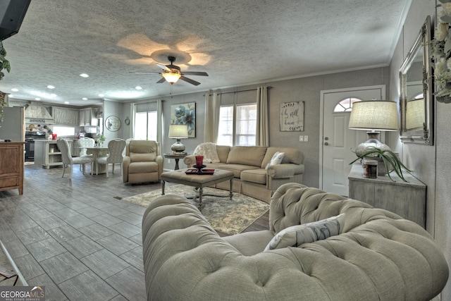 living room with a textured ceiling, ceiling fan, and crown molding