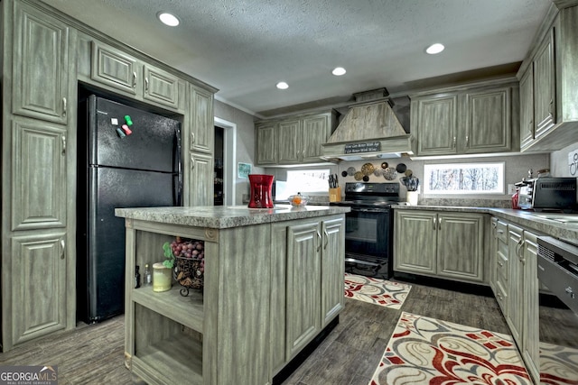 kitchen with dark hardwood / wood-style floors, a textured ceiling, a kitchen island, black appliances, and custom range hood