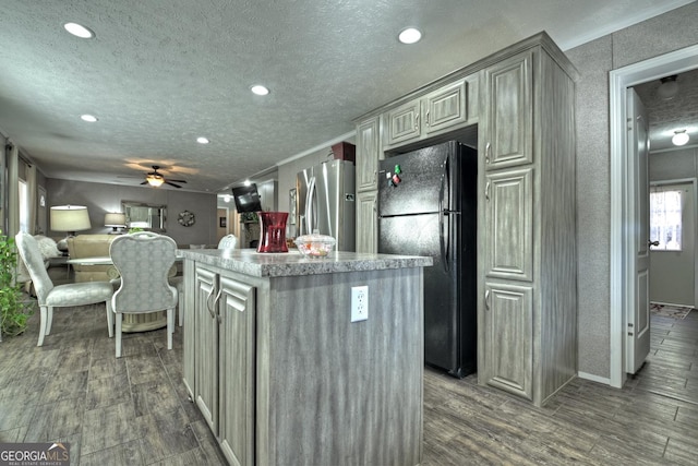 kitchen with black refrigerator, stainless steel refrigerator with ice dispenser, crown molding, a kitchen island, and dark hardwood / wood-style flooring