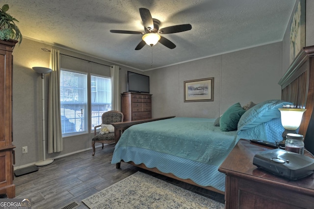 bedroom with a textured ceiling, ceiling fan, wood-type flooring, and ornamental molding