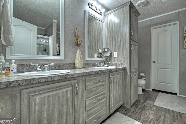 bathroom featuring vanity, hardwood / wood-style flooring, toilet, ornamental molding, and a textured ceiling