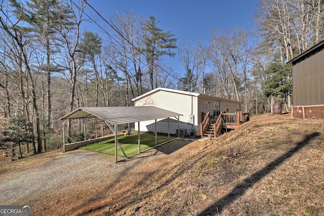 view of side of property featuring a lawn, central AC unit, a deck, and a carport