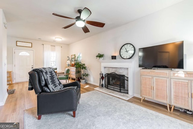 living room featuring a fireplace, light hardwood / wood-style flooring, and ceiling fan