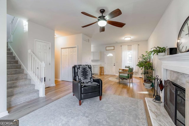 living room with ceiling fan, a fireplace, and light hardwood / wood-style flooring