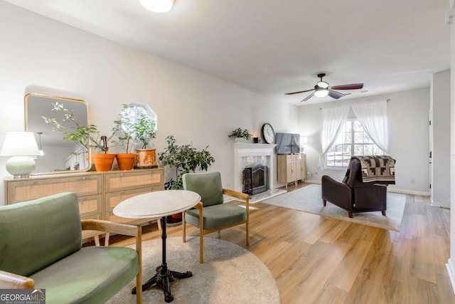 living room featuring ceiling fan, light hardwood / wood-style flooring, and a high end fireplace