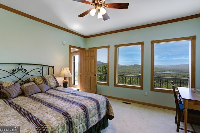 bedroom with a mountain view, light carpet, ceiling fan, and crown molding