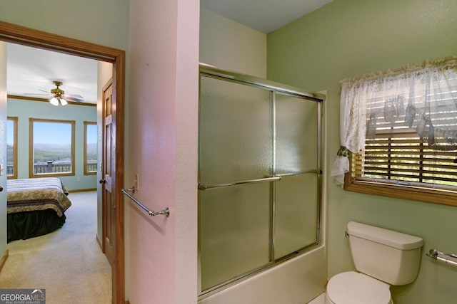 bathroom featuring combined bath / shower with glass door, toilet, and ceiling fan