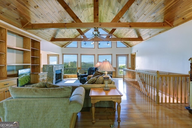 living room featuring plenty of natural light, beam ceiling, and a tile fireplace