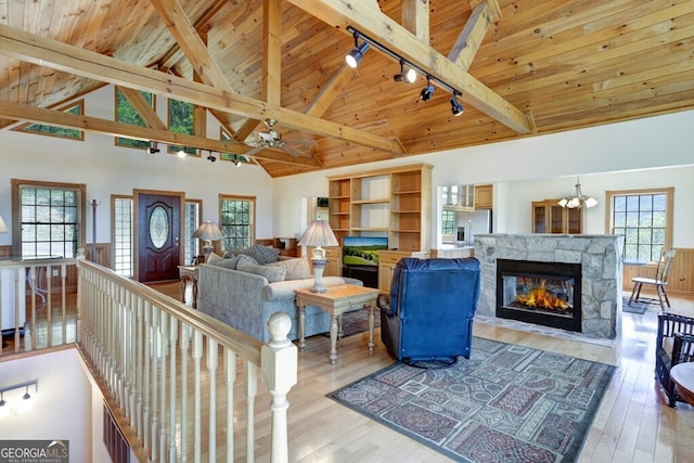 living room with light hardwood / wood-style flooring, beamed ceiling, high vaulted ceiling, a fireplace, and wood ceiling