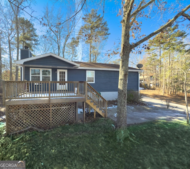 rear view of property featuring a lawn and a wooden deck