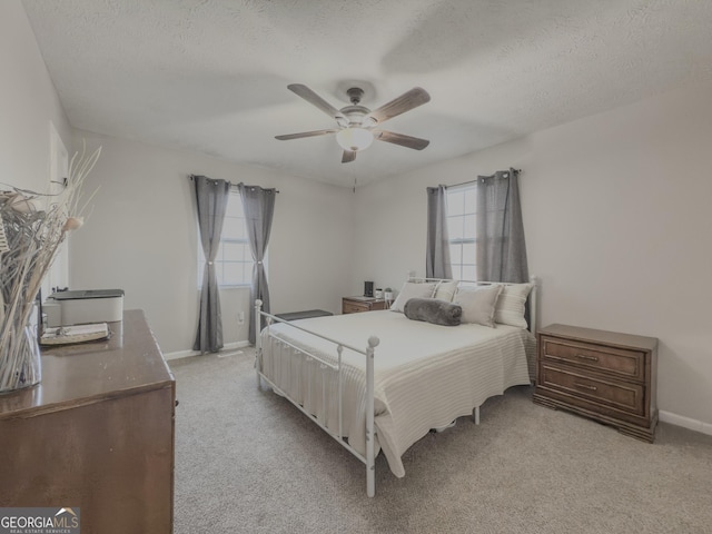 carpeted bedroom featuring multiple windows, ceiling fan, and a textured ceiling