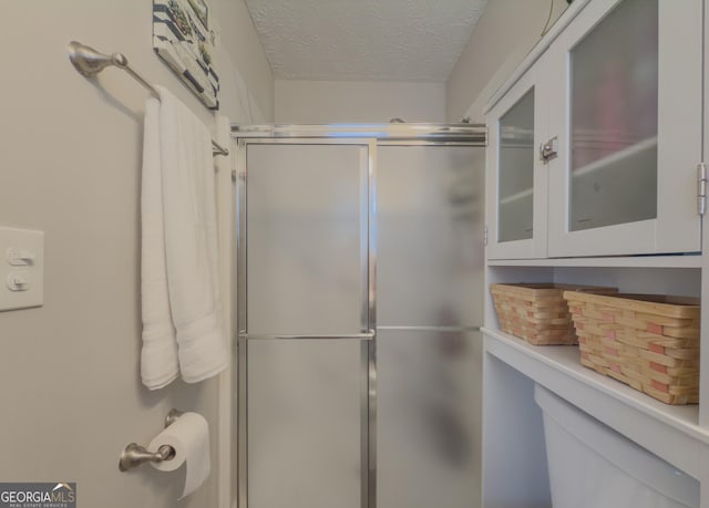 bathroom featuring a textured ceiling and a shower with shower door