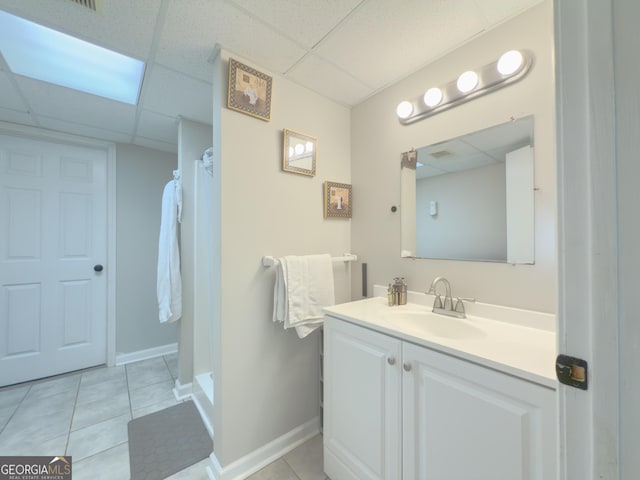 bathroom featuring tile patterned floors, a drop ceiling, walk in shower, and vanity