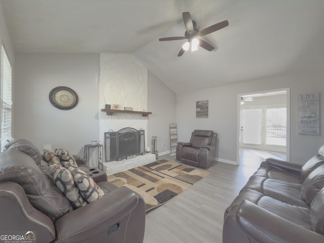 living room with a fireplace, light wood-type flooring, vaulted ceiling, and ceiling fan