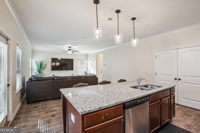 kitchen with pendant lighting, dishwasher, sink, light stone counters, and a center island with sink