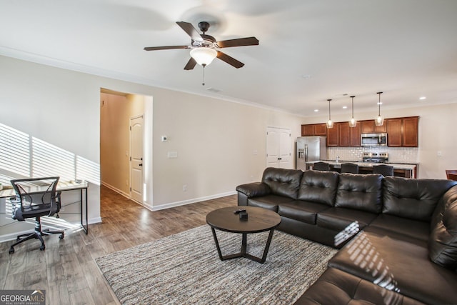 living room with ornamental molding, ceiling fan, and dark wood-type flooring