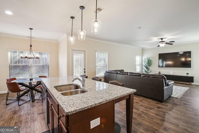 kitchen featuring sink, hanging light fixtures, light stone counters, crown molding, and ceiling fan with notable chandelier