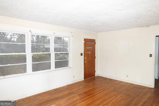 spare room with a textured ceiling and dark hardwood / wood-style flooring